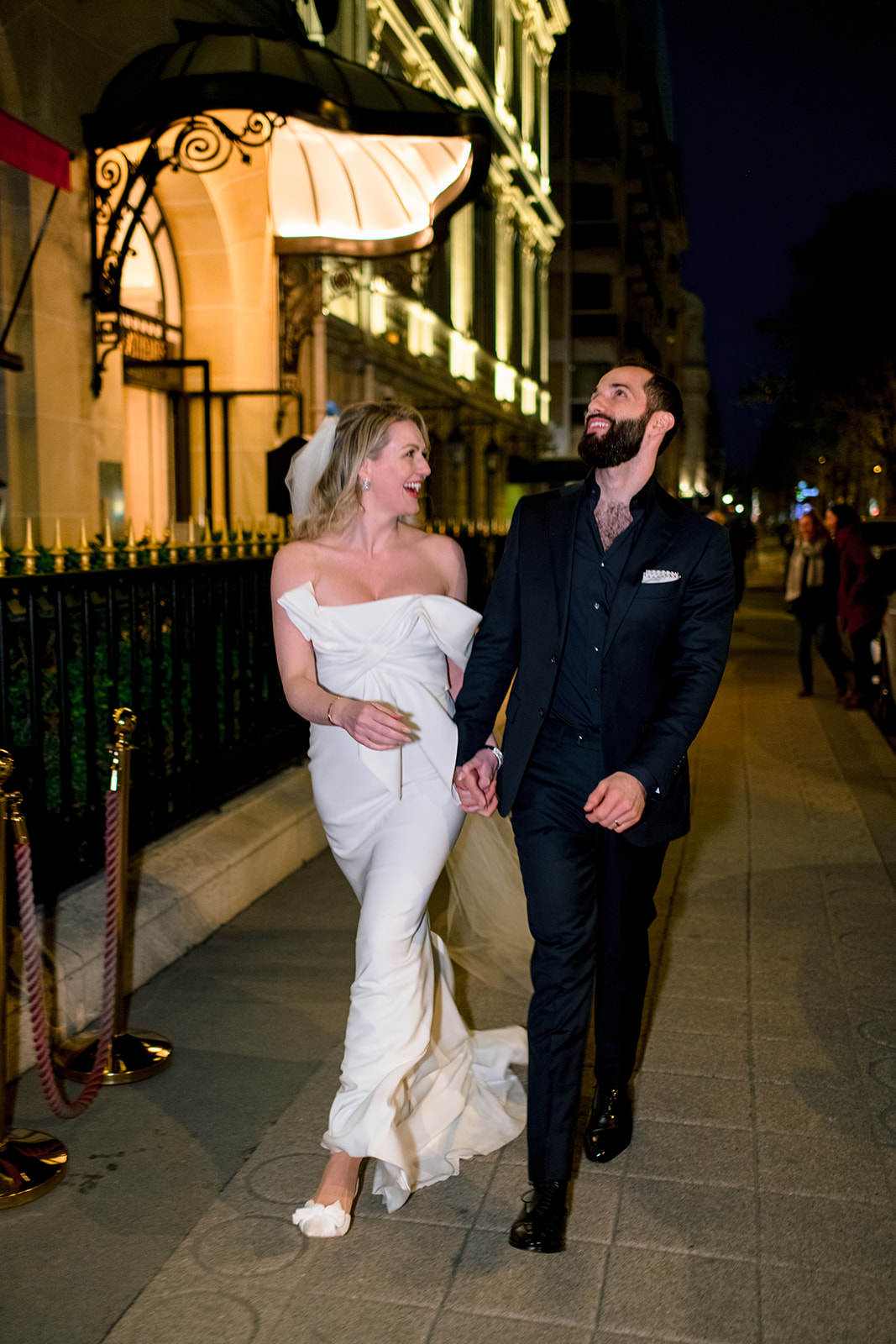 Newlyweds laughing during a night walk outside Hôtel Plaza Athénée